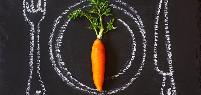 Healthy food concept. Fresh organic carrot on a chalk painted plate.