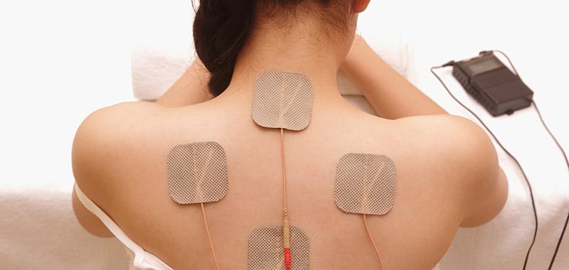 Asian woman is doing massage of electrical -stimulation ( TENs ) for the back