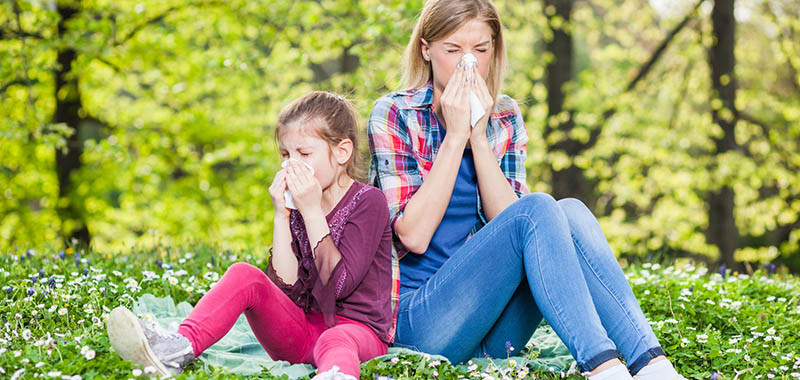 Two people with allergy symptom blow their noses