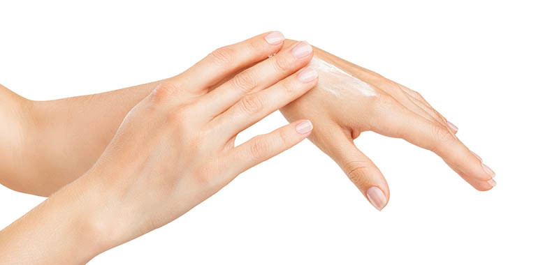 Woman applies cream on her hands isolated on white background